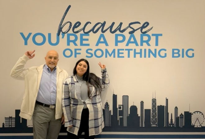Dr. James Frazier and a woman standing in front of and pointing at a mural that says because you’re a part of something big