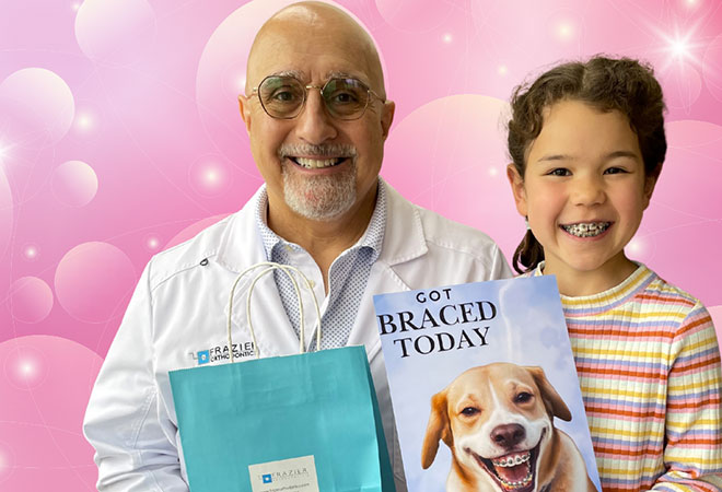 Dr. James Frazier standing with a patient who is holding a sign that says bye-bye braces