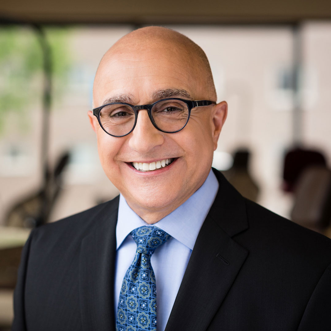 Dr. James Frazier holding a blue gift bag standing next to a young lady patient with braces smiling and holding a sign that says OMG
