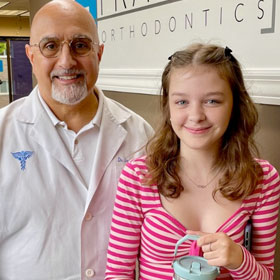 Dr. James Frazier and a young lady patient standing next to each other smiling